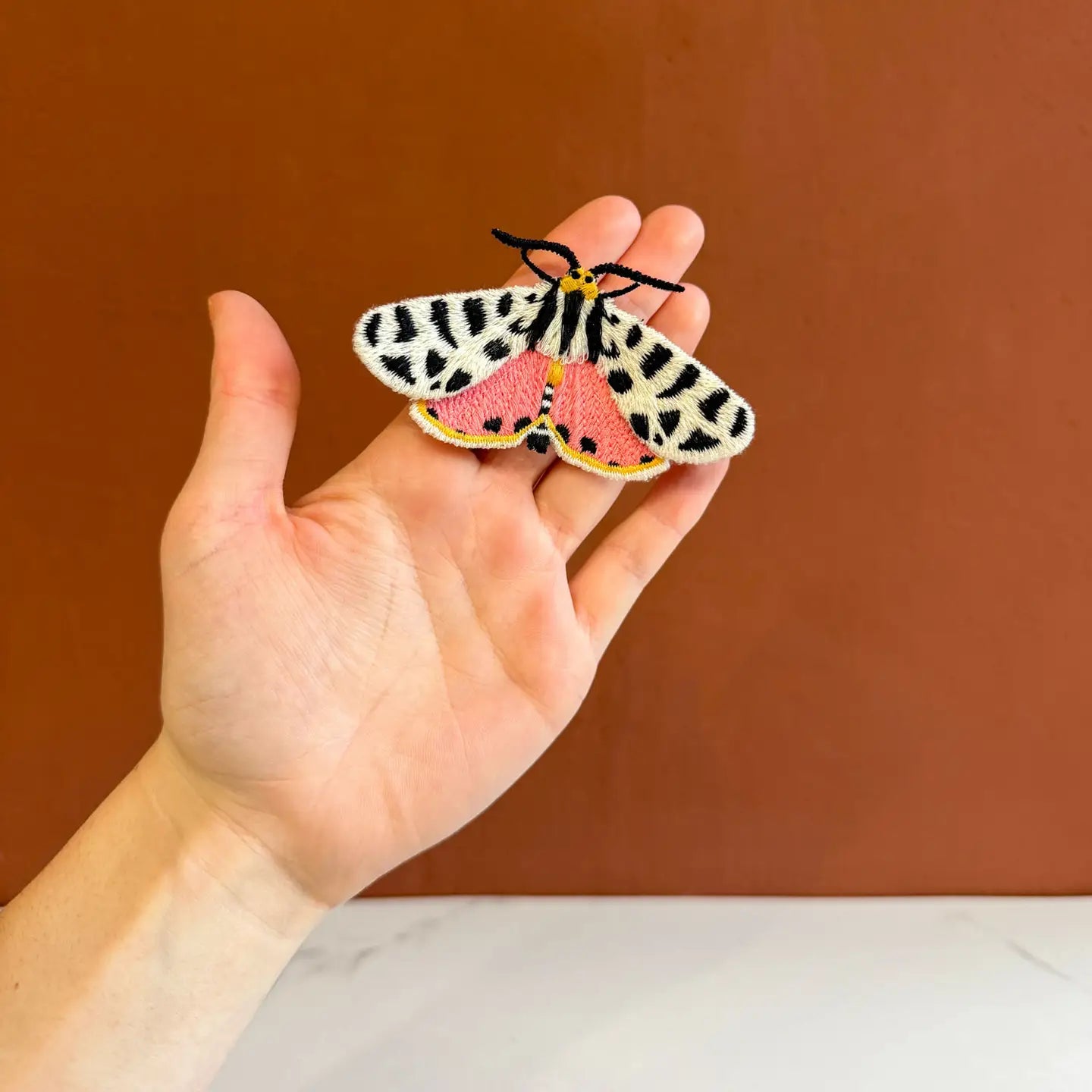 Broszka haftowana Tiger Moth – Botanopia  na dłoni