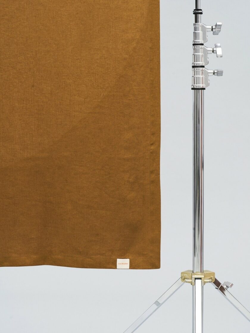 Zbliżenie materiału ręcznika w kolorze brązowym, widoczna naszywka/metka z napisem marki Lazy Beaches.